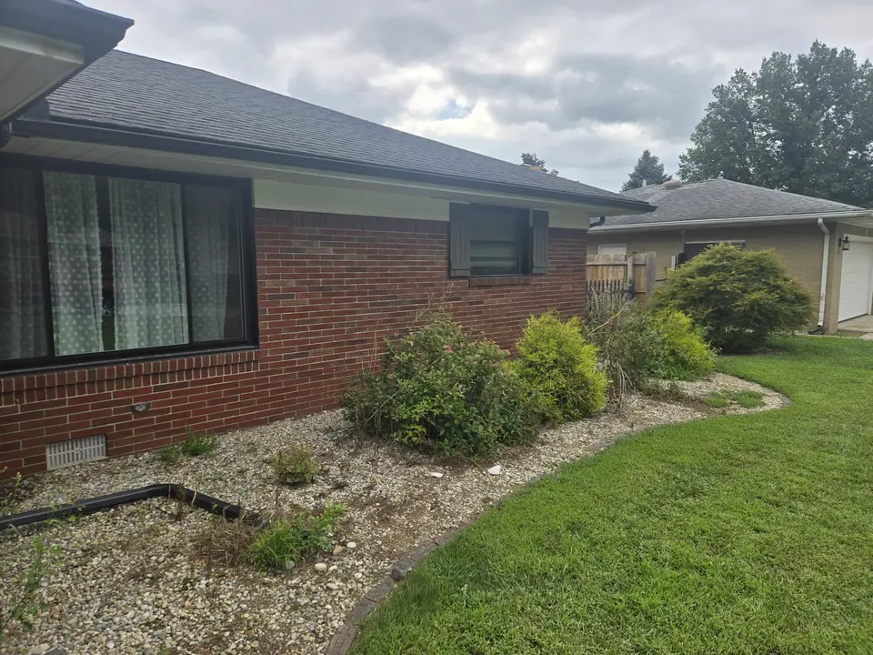 Brick ranch home with a dark shingle roof and a gutter run along the eave.