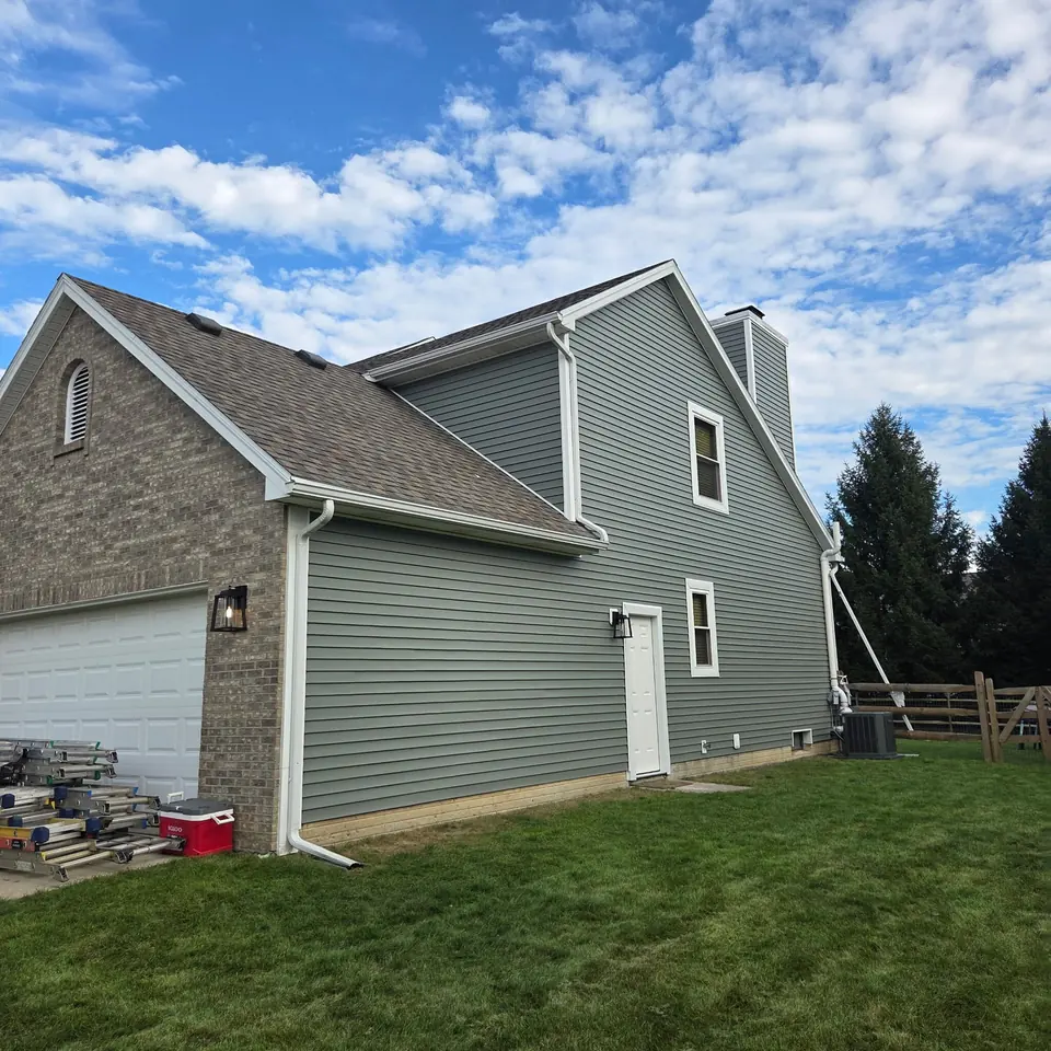 Sage green siding and white trim on a two-story home beside a brick garage.